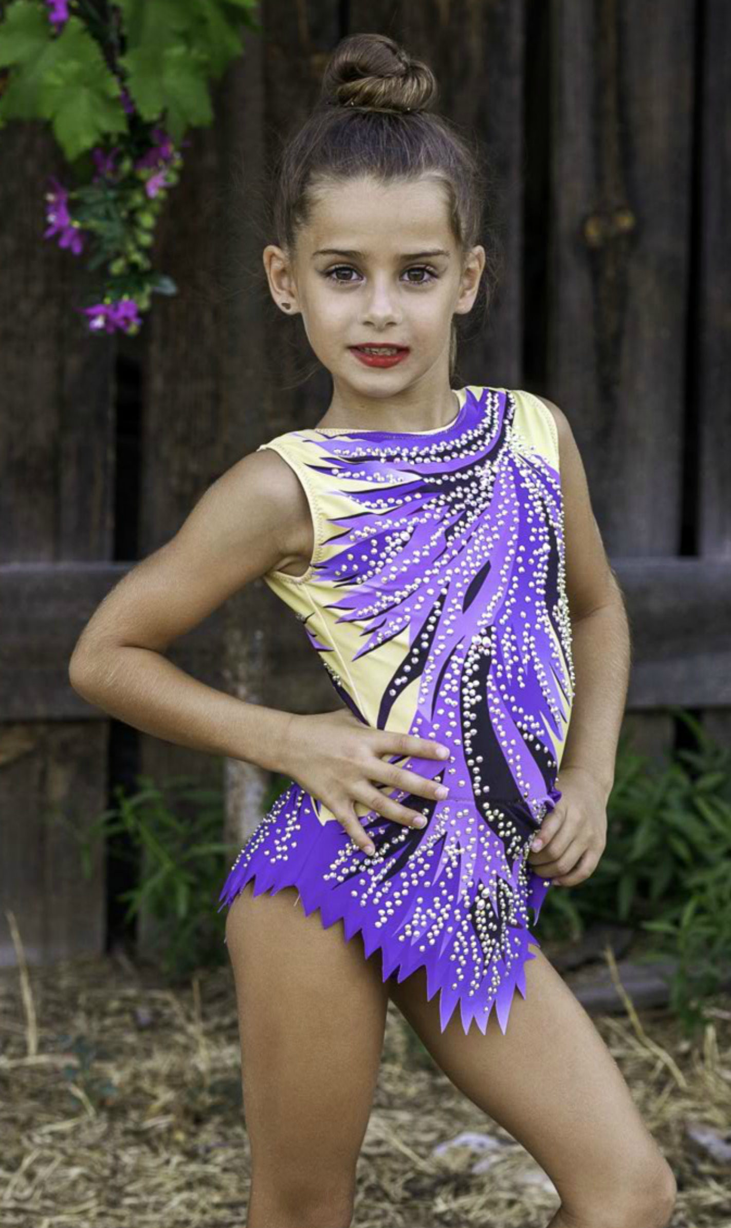 Maillot de gimnasia rítmica en lila, negro y amarillo, decorado con pedrería brillante. Con diseño dinámico y tejido elástico para un ajuste cómodo y espectacular. Ideal para entrenamientos y competiciones.