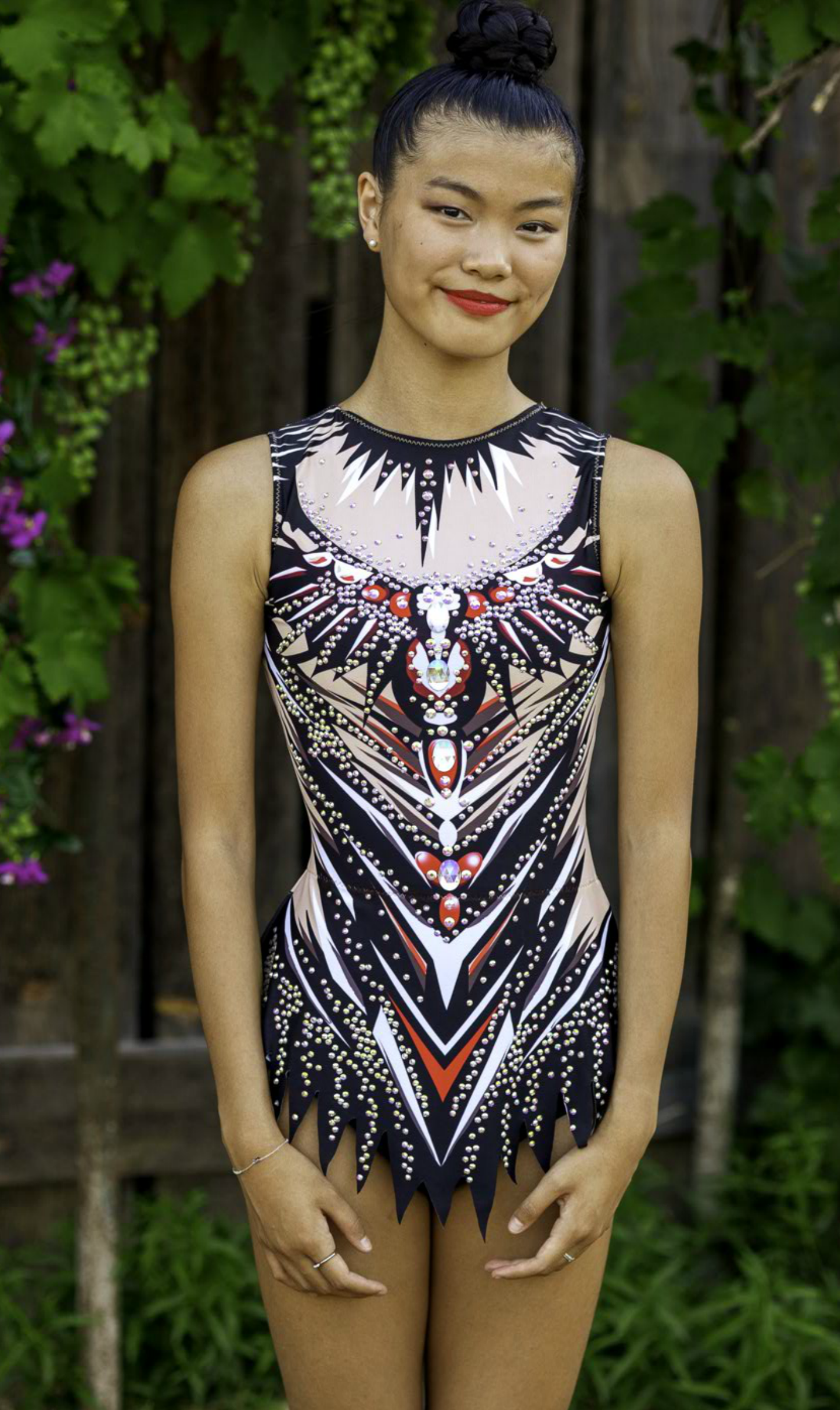 Maillot deportivo impactante con diseño tribal en tonos negro, rojo y nude, decorado con pedrería brillante. Corte cómodo y tejido elástico que se adapta al cuerpo, ideal para competencias de gimnasia, danza o patinaje.